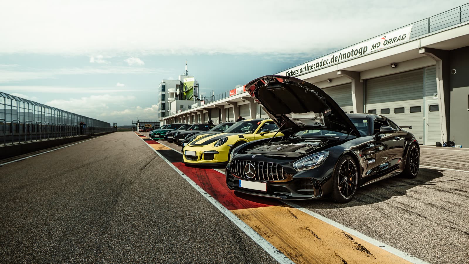 Mercedes-AMG GT R mit geöffneter Motorhaube, Porsche 911 GT3 RS und weitere Sportwagen in der Boxengasse am Sachsenring