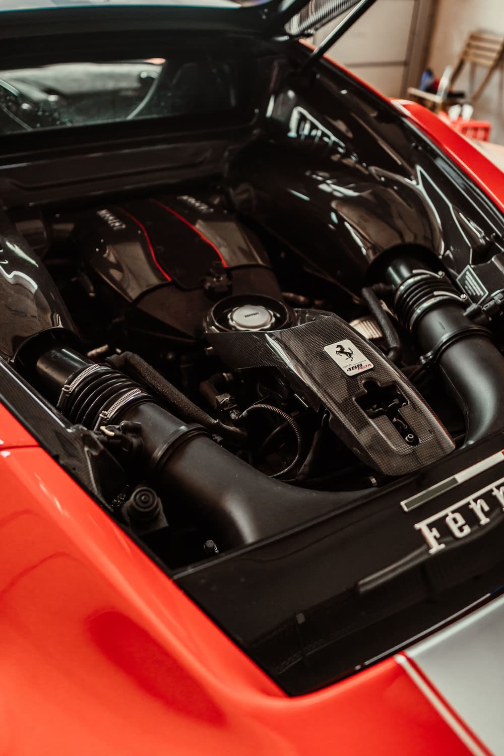 Geöffneter Motorraum eines Ferrari 488 Pista: V8-Biturbo mit Carbon-Abdeckung und Ansaugstrecke